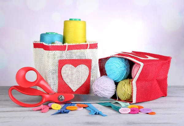 Zakken met spoelkokers van kleurrijke wol en wollen ballen op houten tafel, op lichte achtergrond — Stockfoto