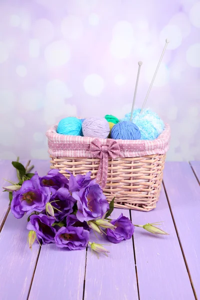 Eustoma artificial púrpura y bolas de lana de hilo en cesta sobre fondo claro —  Fotos de Stock