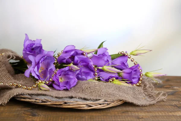 Purple artificial eustoma on sackcloth on color wooden  table, on bright background — Stock Photo, Image