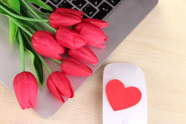 Computadora con corazón rojo y flores en la mesa de cerca — Foto de Stock