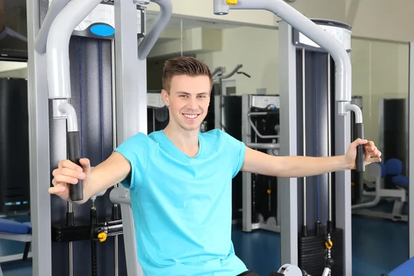 Junger Mann trainiert mit Gewichten im Fitnessstudio — Stockfoto