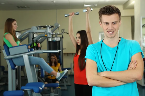 Unga tränare och kvinnans bedriver simulator i gym — Stockfoto