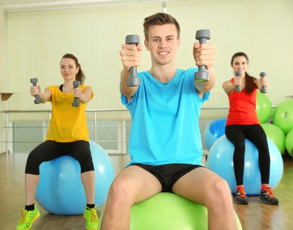 Jeunes belles personnes engagées avec des haltères dans la salle de gym — Photo