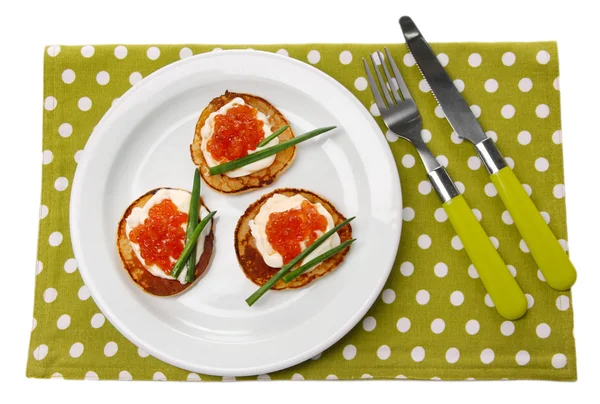 Frittelle con caviale rosso su piatto, su tovagliolo di colore, isolate su bianco — Foto Stock