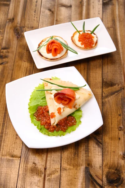 Pancakes with red caviar, salmon and mayo, green onion, on plate, on wooden  table background — Stock Photo, Image