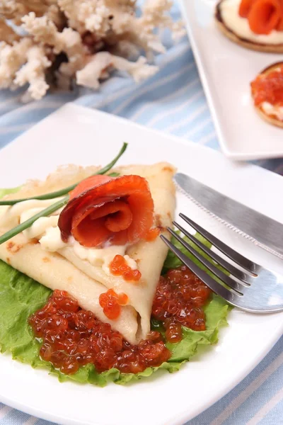 Pannenkoeken met rode kaviaar, zalm en mayo, groene ui, op plaat, op kleur servet, achtergrond — Stockfoto