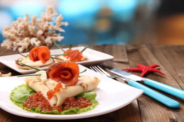 Pancakes with red caviar, salmon and mayo, green onion, on plate, on wooden  table, on bright background — Stock Photo, Image