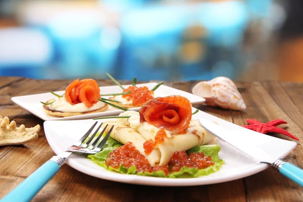 与红鱼子酱，三文鱼和蛋黄酱，葱，放盘子里，木制的桌子，在明亮的背景上煎饼 — 图库照片