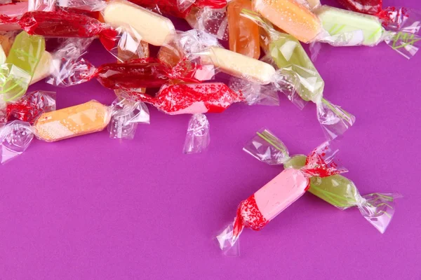 Tasty candies on purple background — Stock Photo, Image