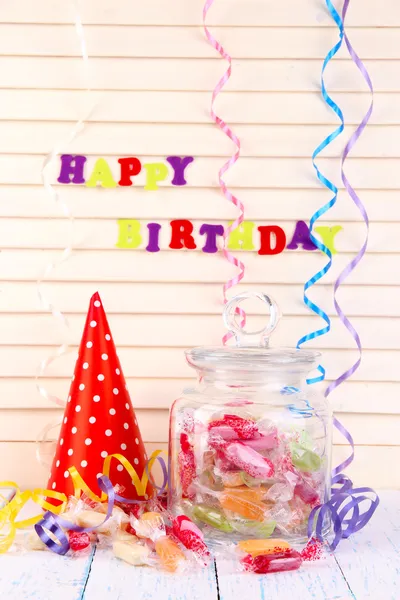 Bonbons savoureux dans un bocal avec chapeau de fête sur la table sur fond en bois — Photo