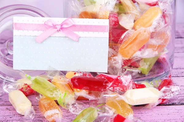 Tasty candies in jar with card on table close up — Stock Photo, Image