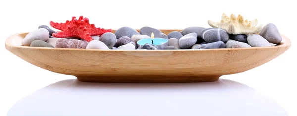 Деревянная чаша со спа-камнями, морскими раковинами и свечами, изолированными на белом — стоковое фото