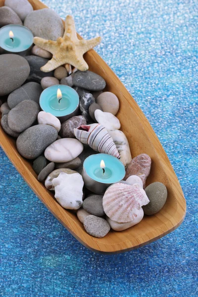 Cuenco de madera con piedras de spa, conchas de mar y velas sobre fondo de color —  Fotos de Stock