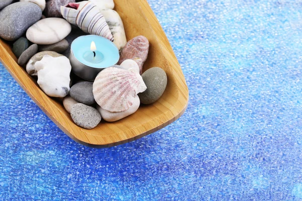 Cuenco de madera con piedras de spa, conchas de mar y velas sobre fondo de color — Foto de Stock