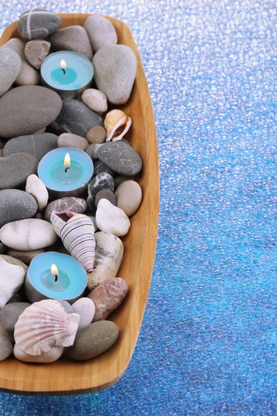 Spa taşlar, deniz kabukları ve mum renkli arka plan üzerinde ahşap kase — Stok fotoğraf