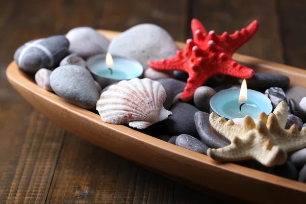 Wooden bowl with Spa stones, sea shells and candles on wooden background — Stock Photo, Image