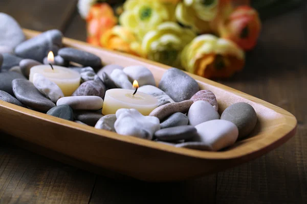 Wooden bowl with spa stones and candles on wooden background — Stock Photo, Image