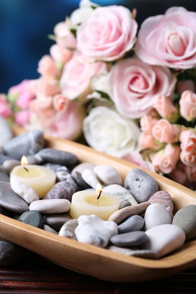 Composição com pedras de spa e velas em tigela de madeira, perto de flores em fundo brilhante — Fotografia de Stock