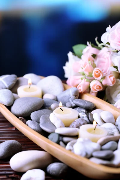 Kompozycja z spa kamienie i świece w drewniane miski, w pobliżu kwiaty na jasnym tle — Zdjęcie stockowe
