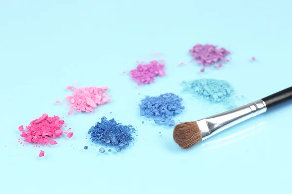 Rainbow crushed eyeshadow and professional make-up brush on blue background — Stock Photo, Image