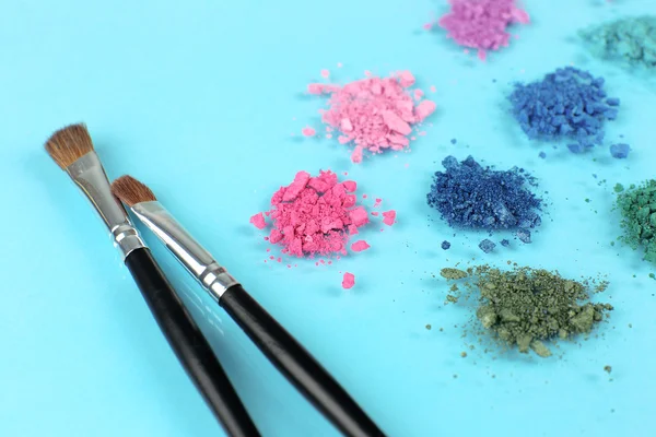 Arco-íris esmagado sombra e escova de maquiagem profissional no fundo azul — Fotografia de Stock