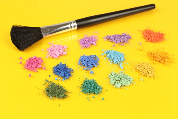 Rainbow crushed eyeshadow and professional make-up brush on yellow background — Stock Photo, Image