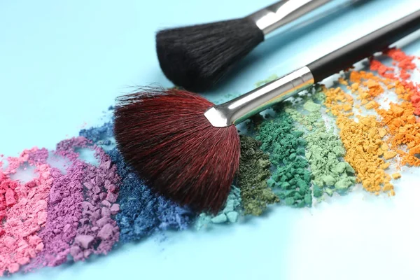 Arco iris triturado sombra de ojos y maquillaje profesional cepillo sobre fondo azul —  Fotos de Stock