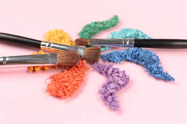 Arco iris triturado sombra de ojos y maquillaje profesional cepillo sobre fondo rosa —  Fotos de Stock