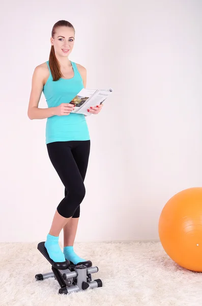 Jovem bela menina fitness se exercitando no stepper no ginásio — Fotografia de Stock