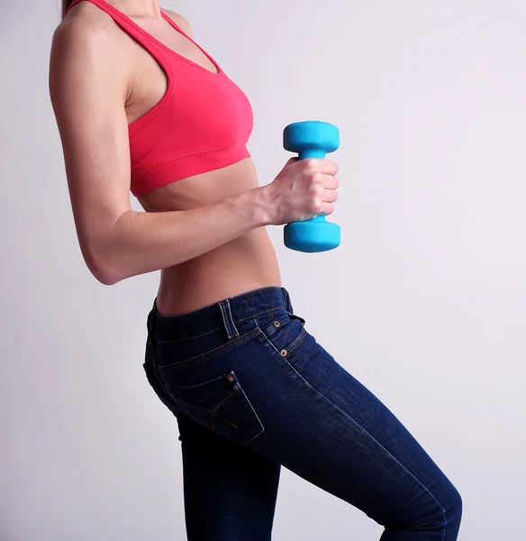 Joven hermosa chica de fitness haciendo ejercicio con pesas, primer plano, sobre fondo gris claro — Foto de Stock
