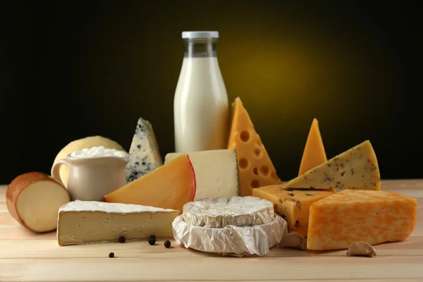 Tasty dairy products on wooden table, on dark background — Stock Photo, Image