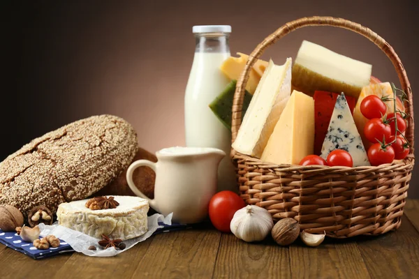 Cesta com produtos lácteos saborosos na mesa de madeira, no fundo escuro — Fotografia de Stock