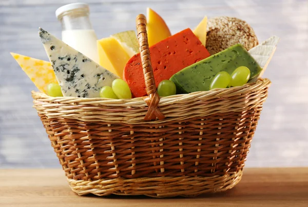 Basket with tasty dairy products on wooden background — Stock Photo, Image