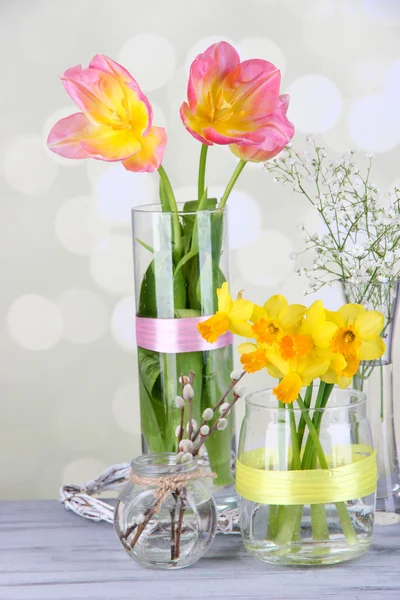 Schöne Frühlingsblumen auf altem Holztisch, auf hellem Hintergrund — Stockfoto