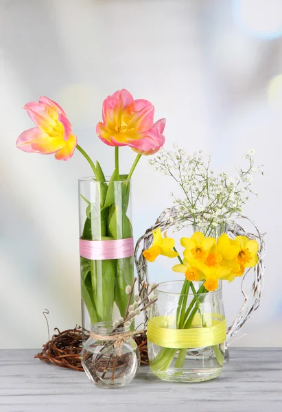 Schöne Frühlingsblumen auf altem Holztisch, auf hellem Hintergrund — Stockfoto