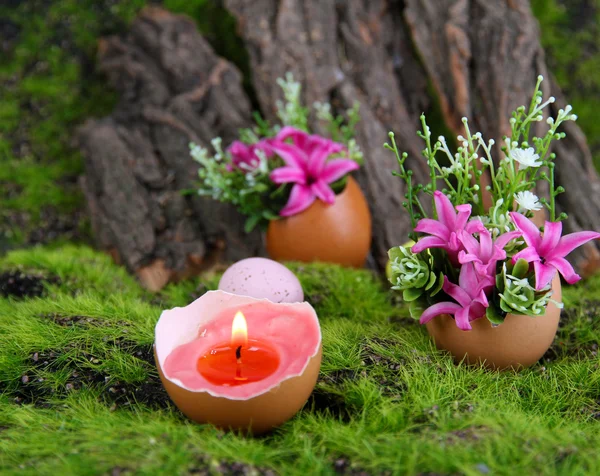 Composição conceitual da Páscoa. Vela ardente em ovo e flores no fundo de grama verde, close-up — Fotografia de Stock