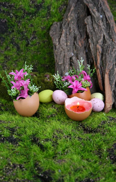Composition conceptuelle de Pâques. Bougie brûlante dans l'œuf et les fleurs sur fond d'herbe verte, gros plan — Photo