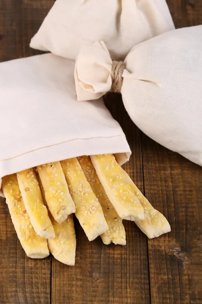 Bread sticks  in sack on wooden background — Stock Photo, Image