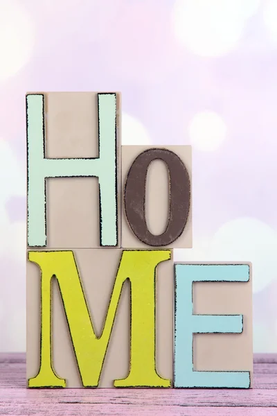 Lettere decorative che formano la parola HOME sul tavolo su sfondo luminoso — Foto Stock