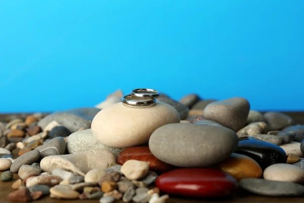 Anneaux de mariage sur des rochers sur fond bleu — Photo