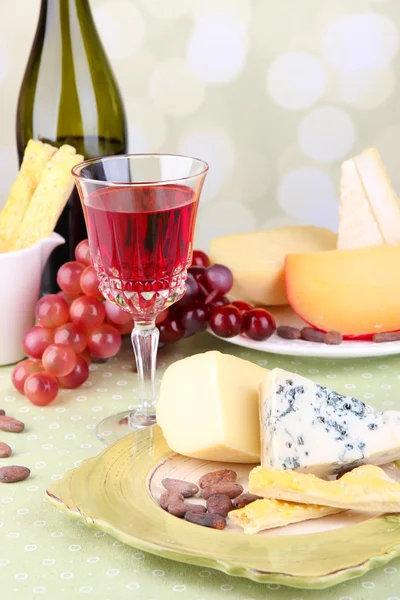 Assorted cheese plate , grape and wine glass on table, on light background — Stock Photo, Image