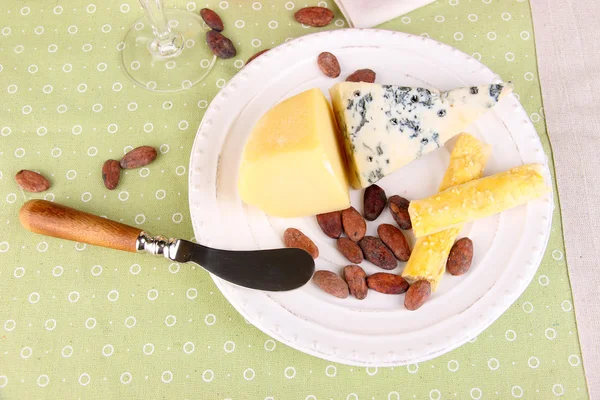 Verschiedene Käseteller, Kakaobohnen und Trauben auf Tischdecke Hintergrund, Nahaufnahme — Stockfoto