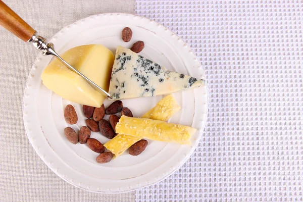 Prato de queijo variado, grãos de cacau e uva em fundo de toalha de mesa, close-up — Fotografia de Stock