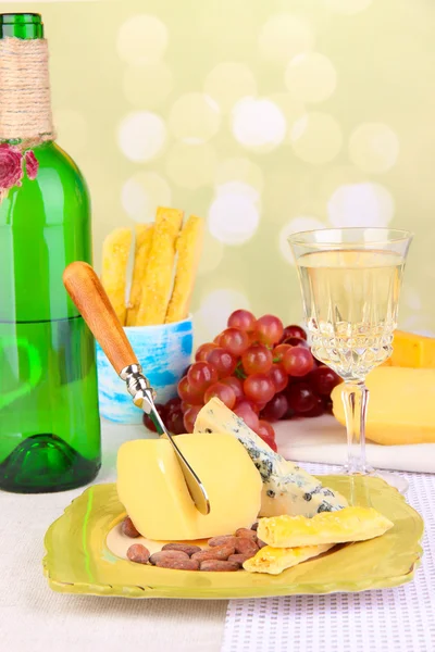 Různé sýrové talíře, hrozny a víno sklenice na stole, na světlém pozadí — Stock fotografie