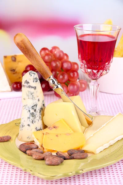 Placa de queso surtido, copa de uva y vino en la mesa, sobre fondo claro — Foto de Stock