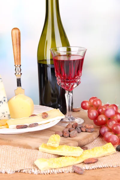 Assorted cheese plate , grape and wine glass on table, on light background — Stock Photo, Image