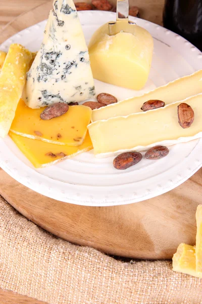 Assorted cheese plate and wine glass on table background — Stock Photo, Image