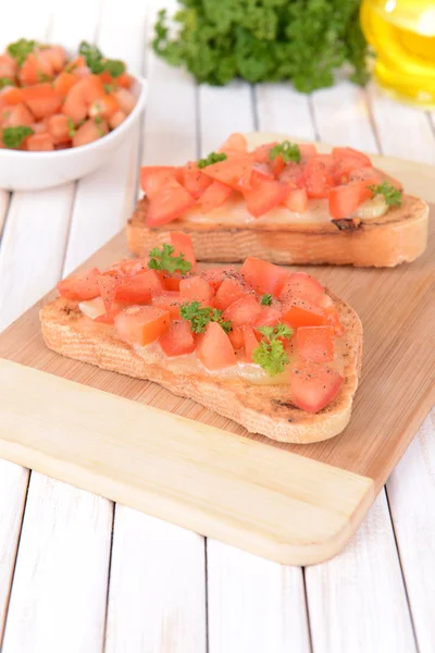 Delicious bruschetta with tomatoes on cutting board close-up — Stock Photo, Image