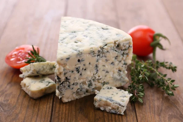 Smakelijke blauwe kaas met tijm en tomaat, op houten tafel — Stockfoto