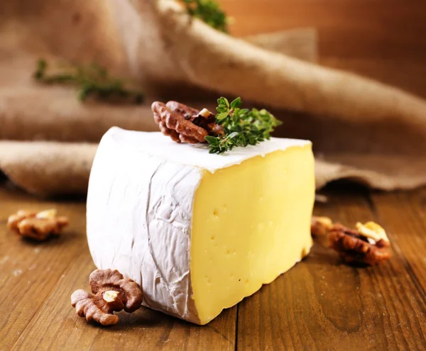 Sabroso queso Camembert con tomillo y nueces, sobre mesa de madera —  Fotos de Stock